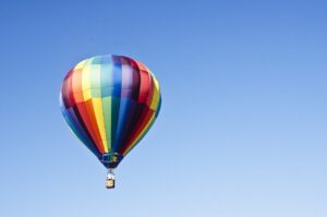 Bunter Heißluftballon schwebt vor blauem Himmel – Symbol für spielerisches Lernen und Perspektivwechsel.