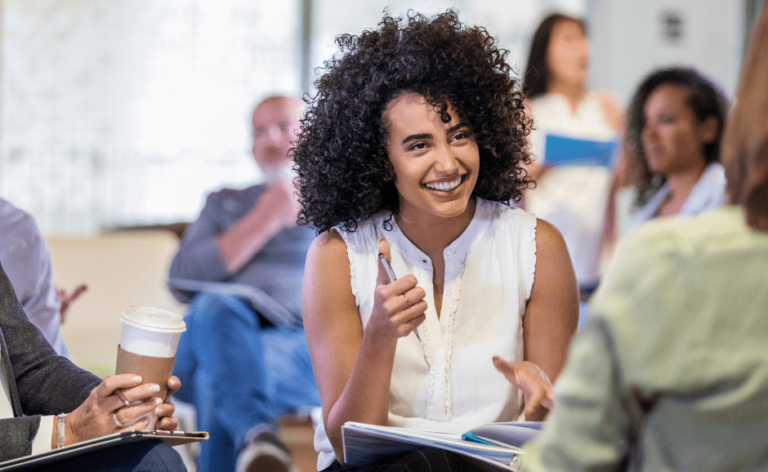 Teilnehmerin in einem Workshop für kreative Schreibmethoden notiert Gedanken und beteiligt sich aktiv am Austausch.