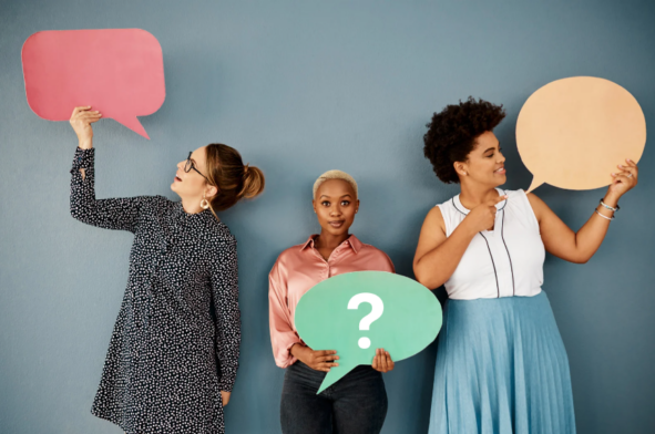 Drei Personen stehen vor blauem Hintergrund und halten verschiedenfarbige Sprechblasen sowie ein Fragezeichen in der Hand.