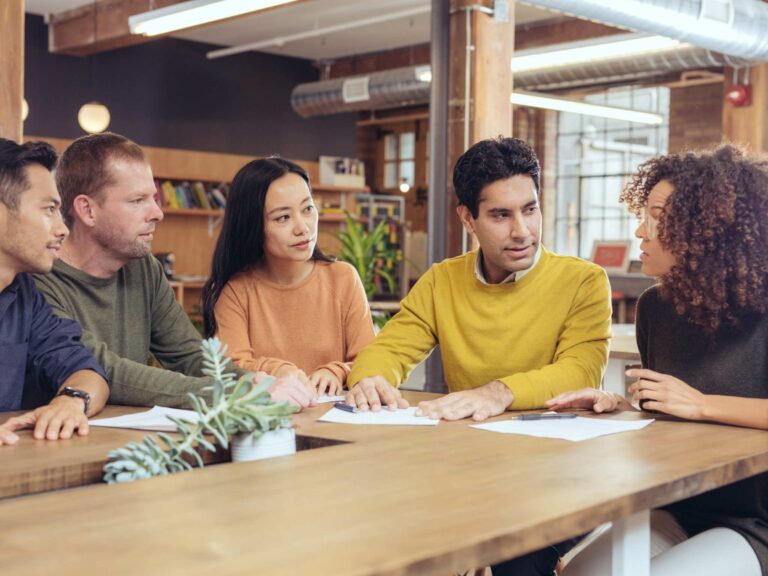 Eine Gruppe erwachsener Personen sitzt gemeinsam am Tisch und führt ein Gespräch.