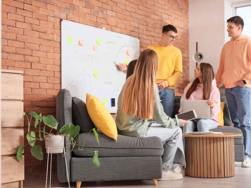 Gruppe arbeitet vor Magnettafel mit Karteikarten, diskutiert Ideen und analysiert Inhalte gemeinsam.