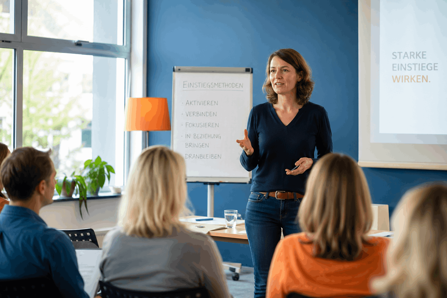 Einstiegsmethoden im Unterricht – Trainerin startet Seminar mit aktivem Impuls vor Gruppe